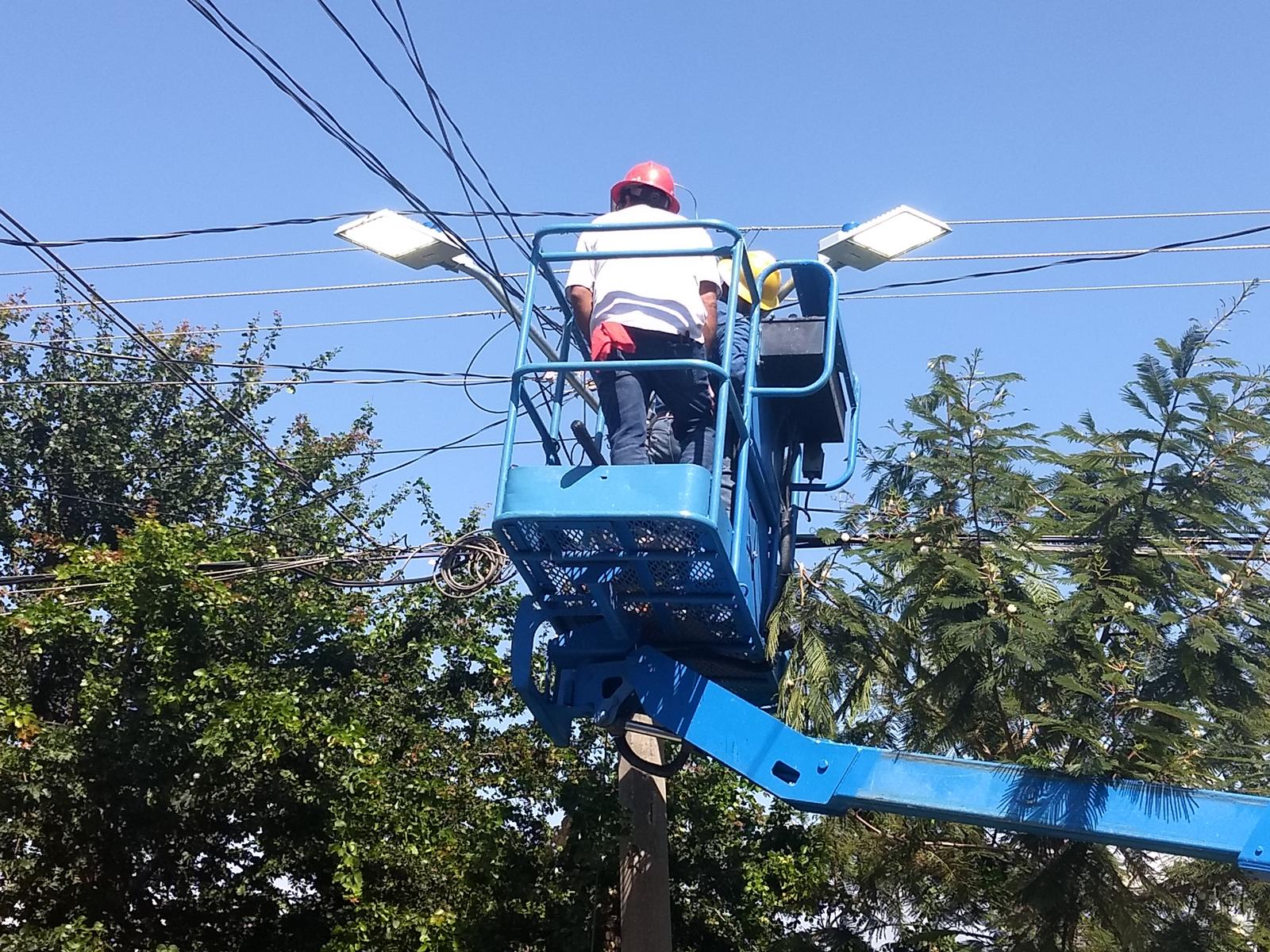 Técnico en una canastilla instalando luminarias de alumbrado público